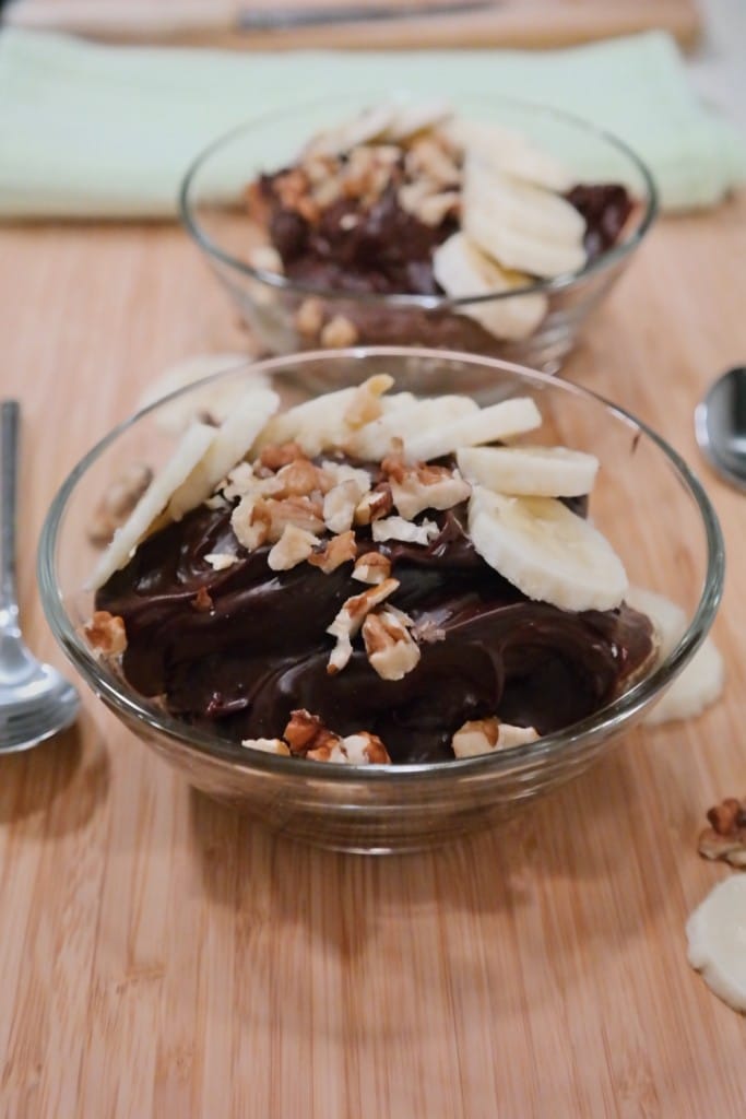 Two bowls of chocolate and peanut butter pudding with banana and nuts