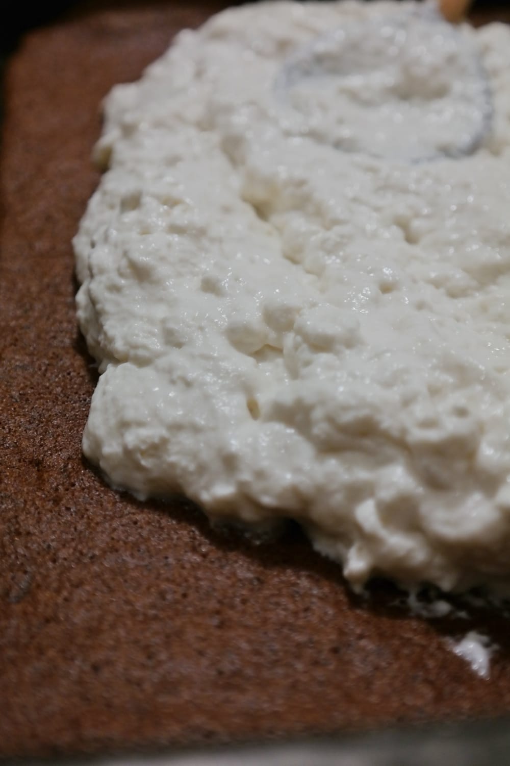 Milk cream spread over the chocolate sponge layer for Kinder Milk Slice