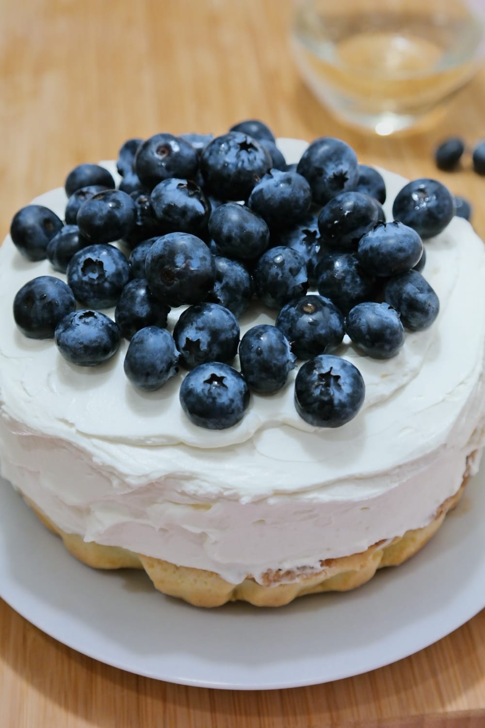 Mini-tort pe o farfurie albă, cu blat vizibil la bază, strat generos de cremă de mascarpone și afine deasupra