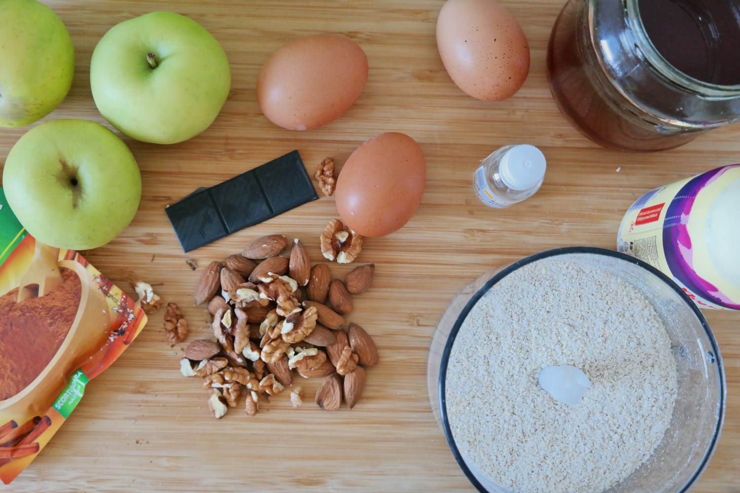 Ingrediente pentru chec cu mere fara zahar, inclusiv mere, oua, ovaz macinat, nuci, migdale si ciocolata neagra