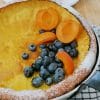 Dutch Baby Pancake served with fresh blueberries, apricots and powdered sugar.