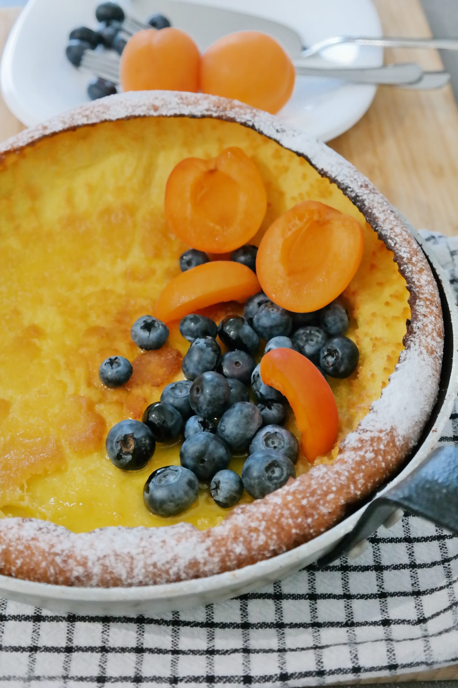 Dutch Baby Pancake served with fresh blueberries, apricots and powdered sugar.
