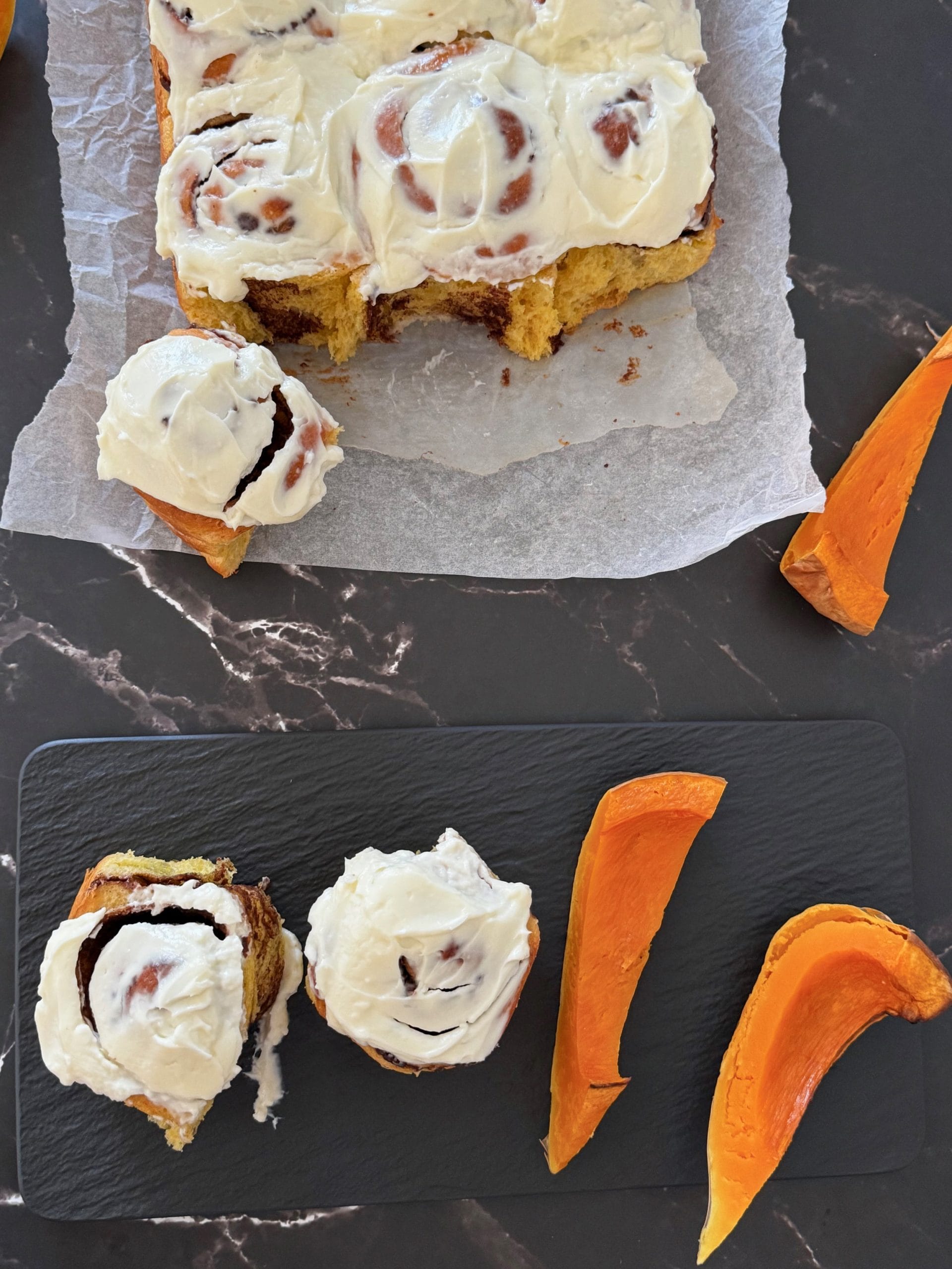 Pumpkin cinnamon rolls with cream cheese frosting served with roasted pumpkin