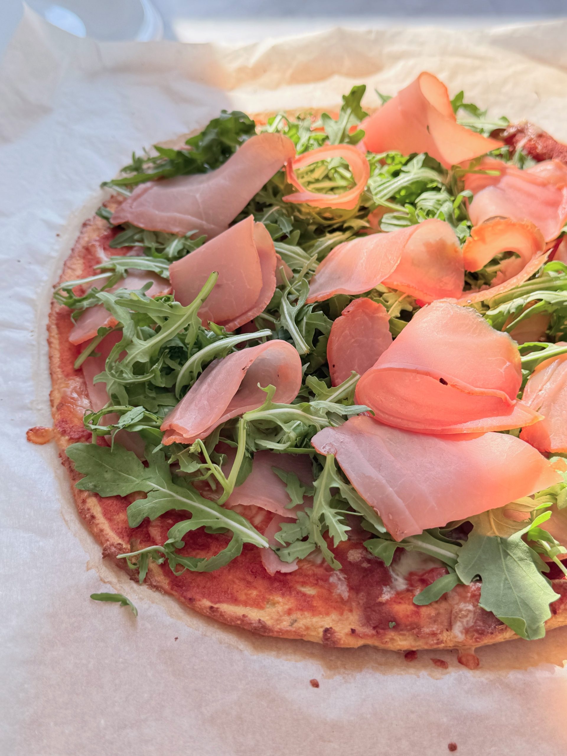 High-protein pizza with prosciutto crudo and arugula