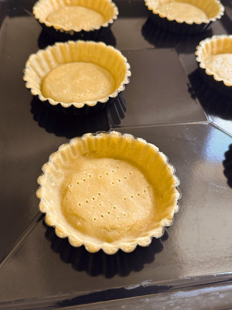 Pricking the tart dough with a fork in the molds before baking