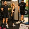 Cartoon illustration of a woman and her husband saying goodbye to their first personal trainer as he leaves the gym.