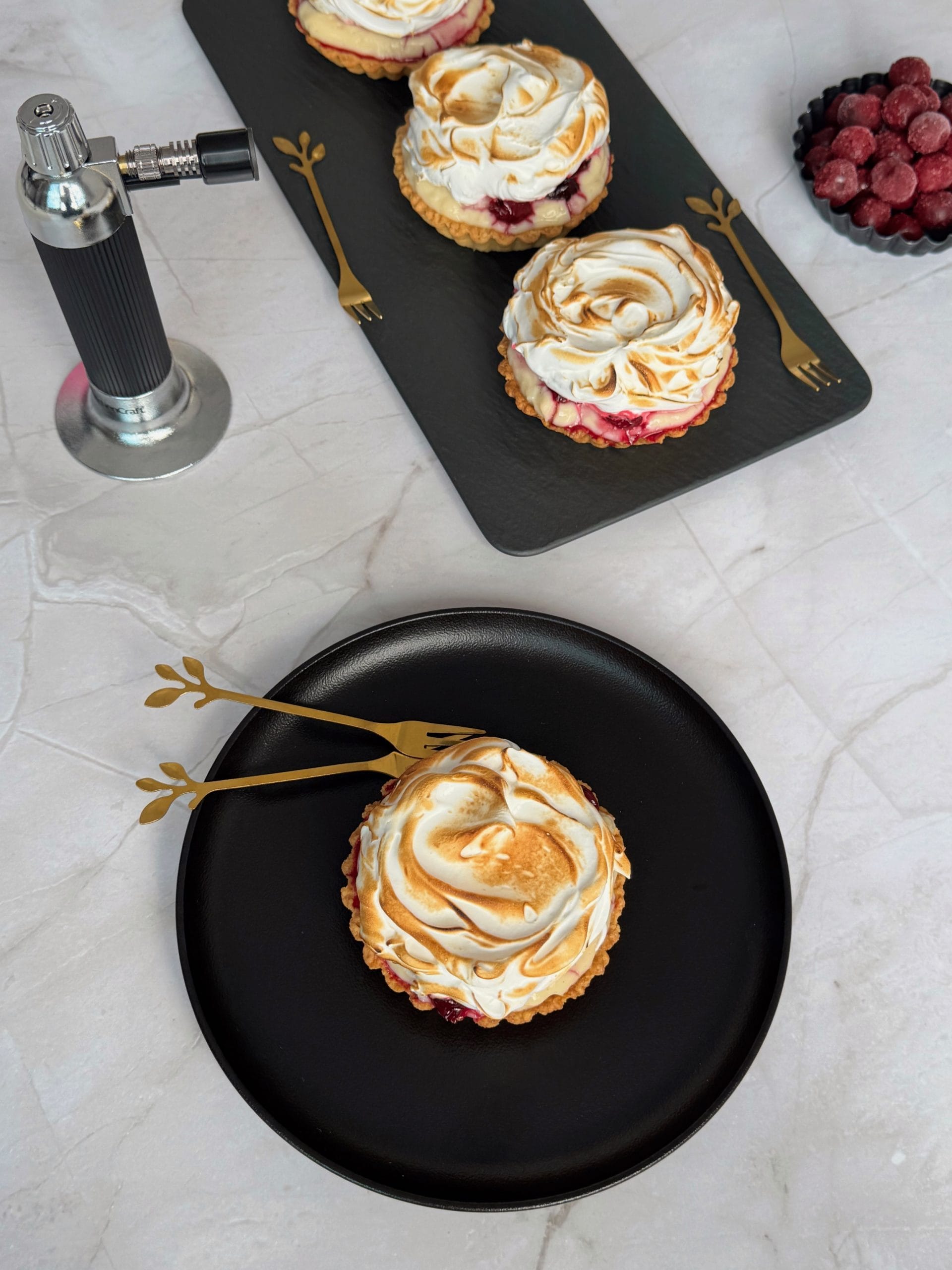 Mini tart with flamed meringue served on a black plate