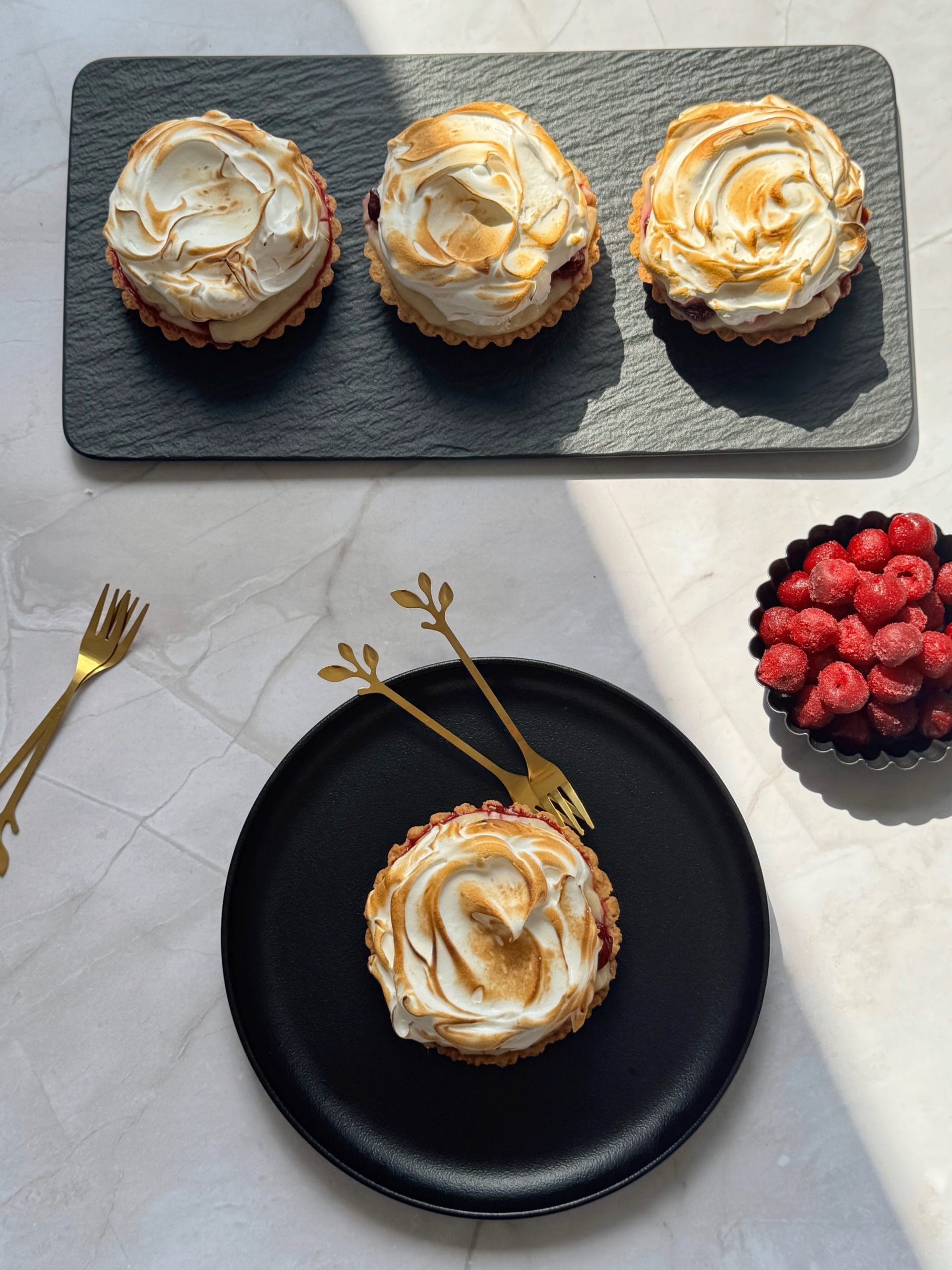 Final food styling of mini sour cherry tarts with flamed meringue