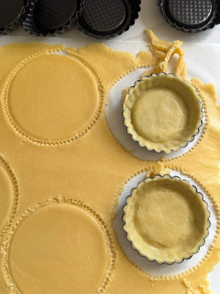Placing tart dough circles into fluted mini tart molds