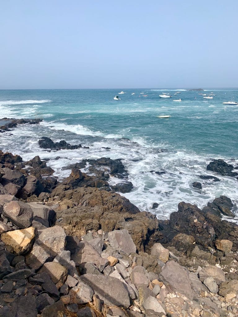 Coasta stancoasa vulcanica cu ape turcoaz si barci ancorate in Tenerife