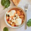 O portie de shakshuka cu cartofi si spanac, oua posate si feta servita in bol