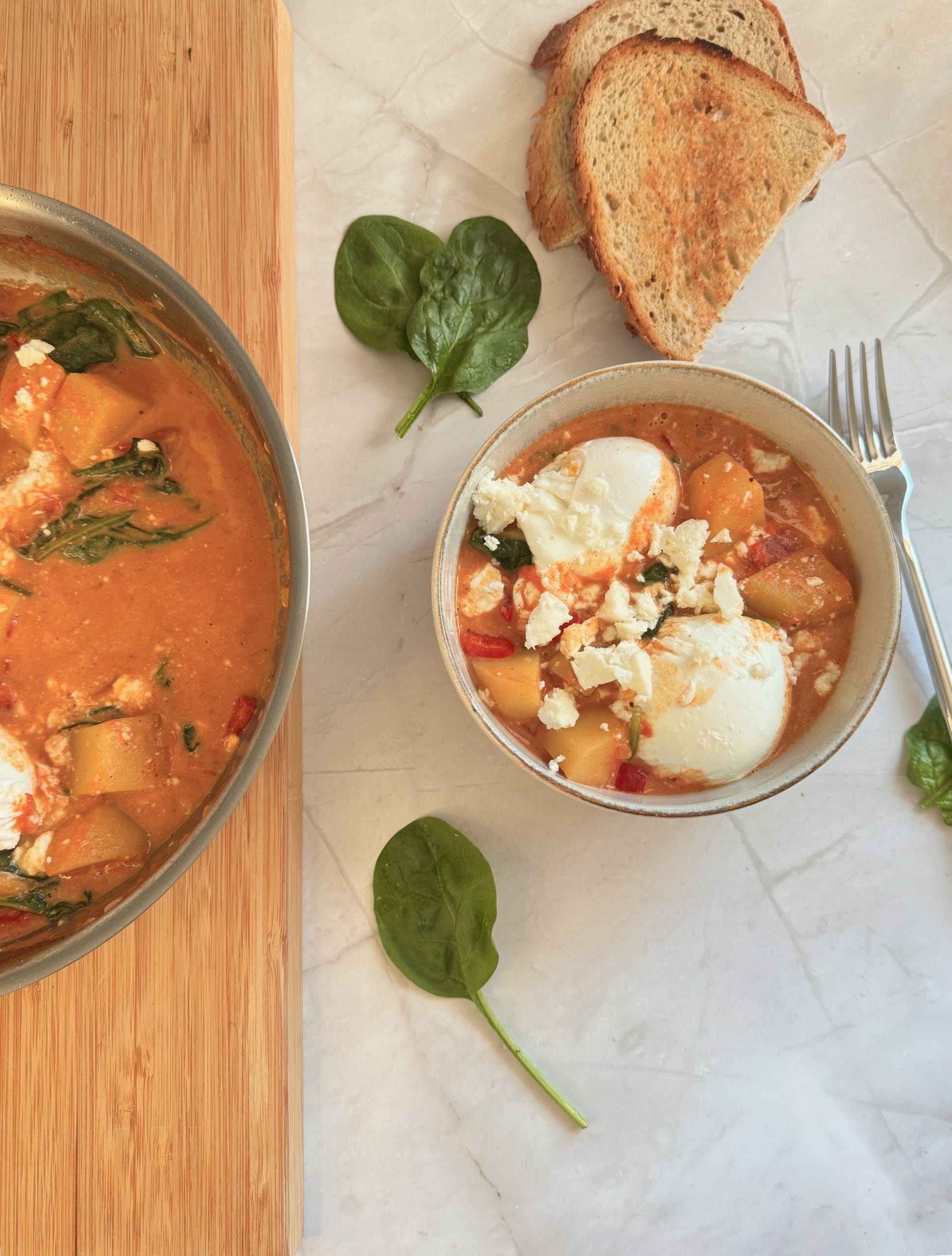 Creamy potato shakshuka served in a bowl next to the cooking pan