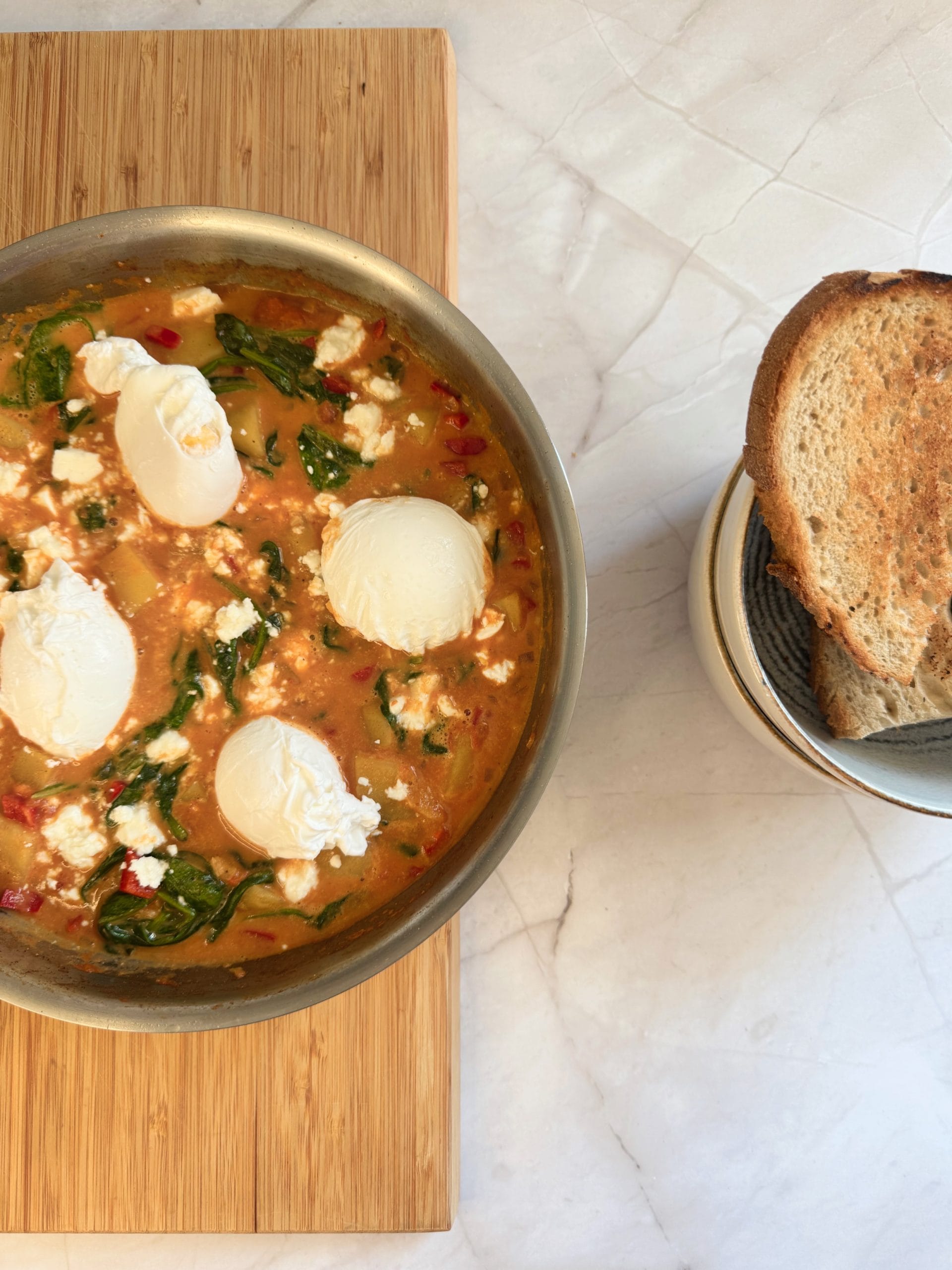 Shakshuka with potatoes, spinach, and feta, served with toast