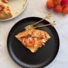 Felie de galeta cu caise si crema de vanilie, servita pe o farfurie neagra