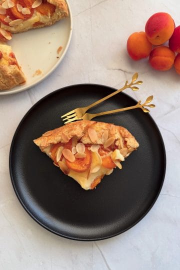 Felie de galeta cu caise si crema de vanilie, servita pe o farfurie neagra