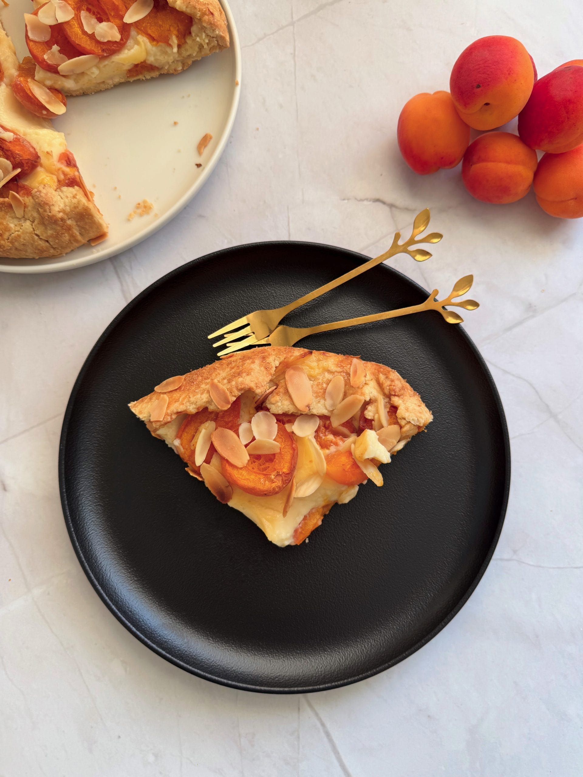 Felie de galeta cu caise si crema de vanilie, servita pe o farfurie neagra