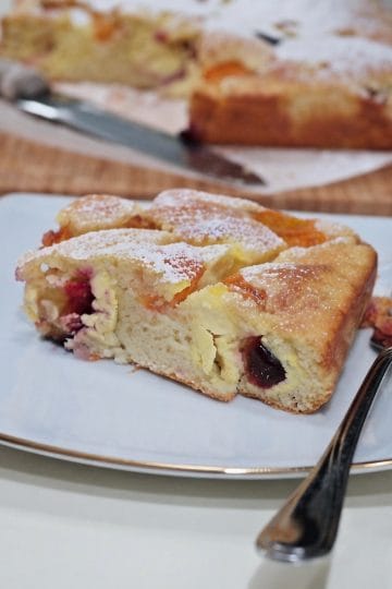 A close-up of a slice of apricot, plum and ricotta cake served on a plate