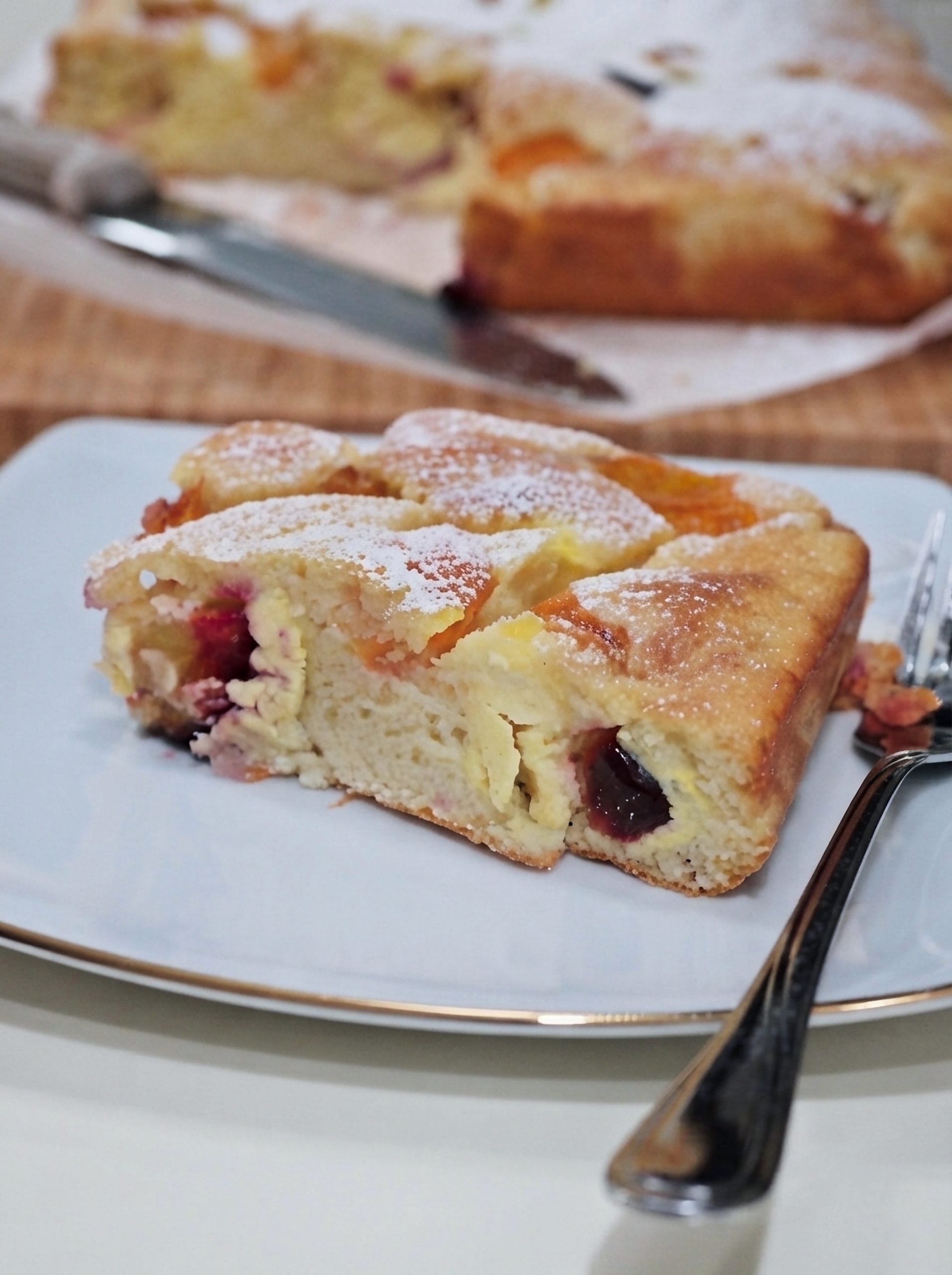 A close-up of a slice of apricot, plum and ricotta cake served on a plate