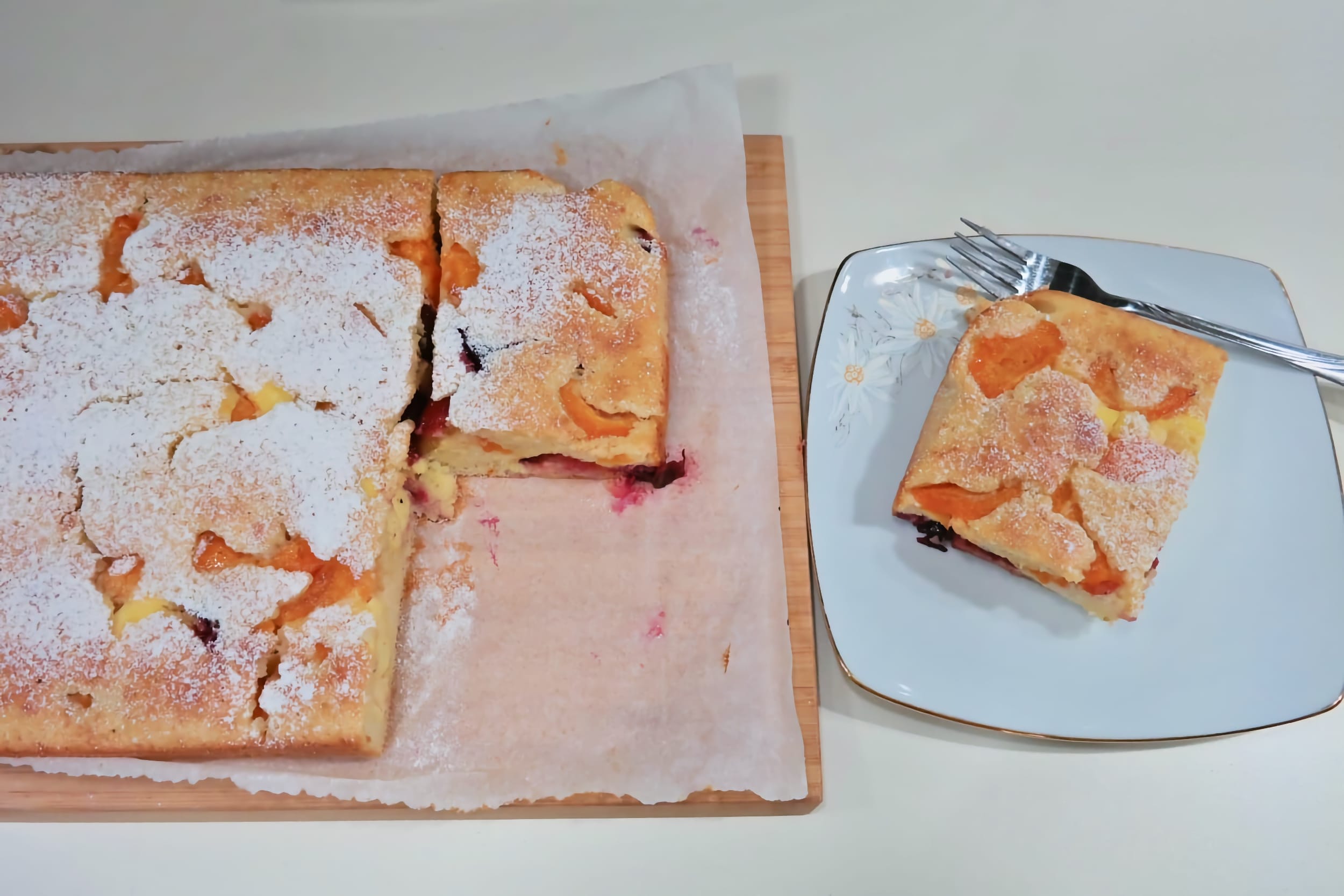 Whole apricot, plum and ricotta cake served alongside a slice on a plate