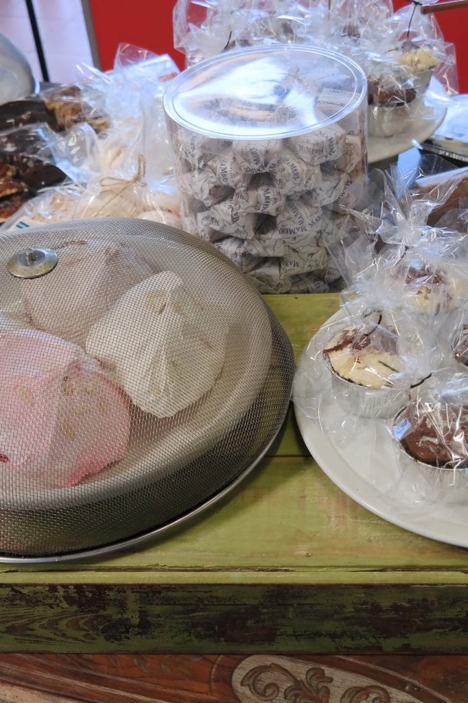 O masa rustica din lemn din interiorul brutariei, pe care sunt expuse diverse produse de patiserie ambalate si neambalate, precum briose si bezele in Cape Town.