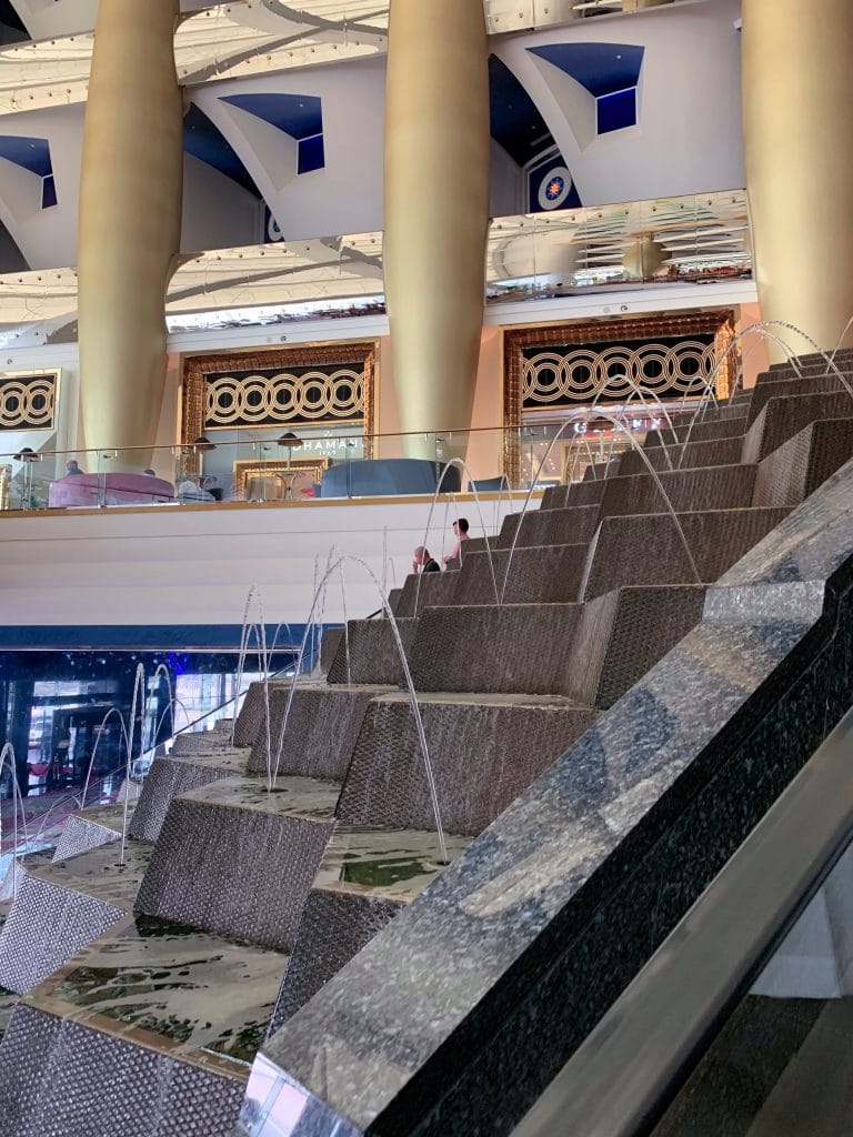 Vedere interioara din Burj al Arab ce surprinde o fantana arteziana in trepte si coloane masive placate cu aur