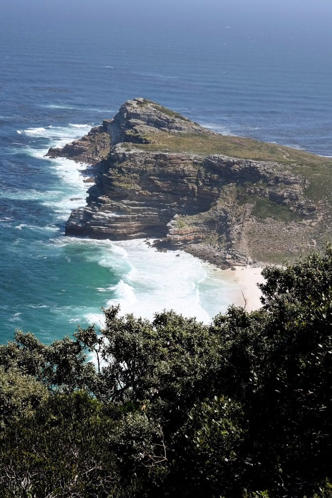 O stanca abrupta care se intinde spre oceanul albastru, vazuta de pe o inaltime acoperita de vegetatie in Cape Town.