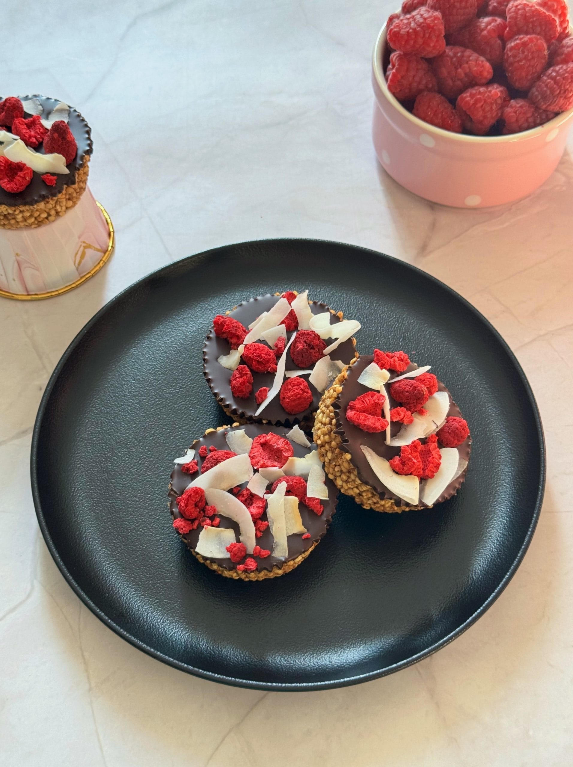 Trei deserturi fara coacere cu quinoa expandata si ciocolata, decorate cu zmeura liofilizata si fulgi de cocos
