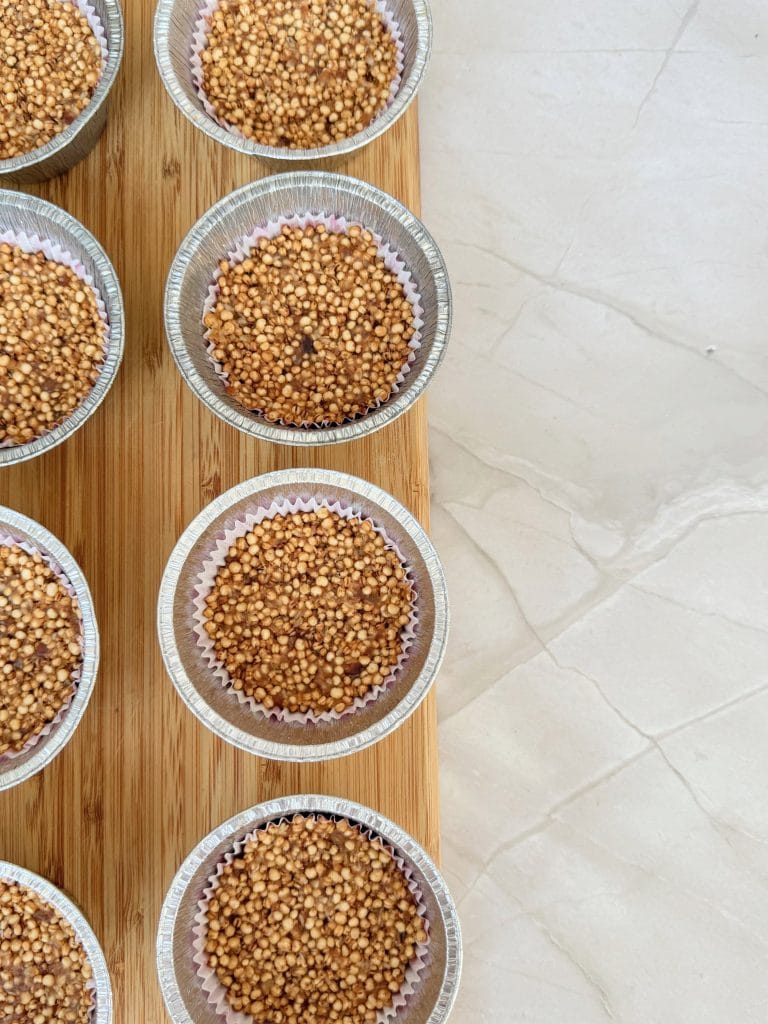 Amestec din quinoa expandata si curmale presat in forme de briose inainte de a adauga stratul de ciocolata
