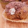 Close up of a pumpkin muffin showing the cream cheese filling and cinnamon crumble topping