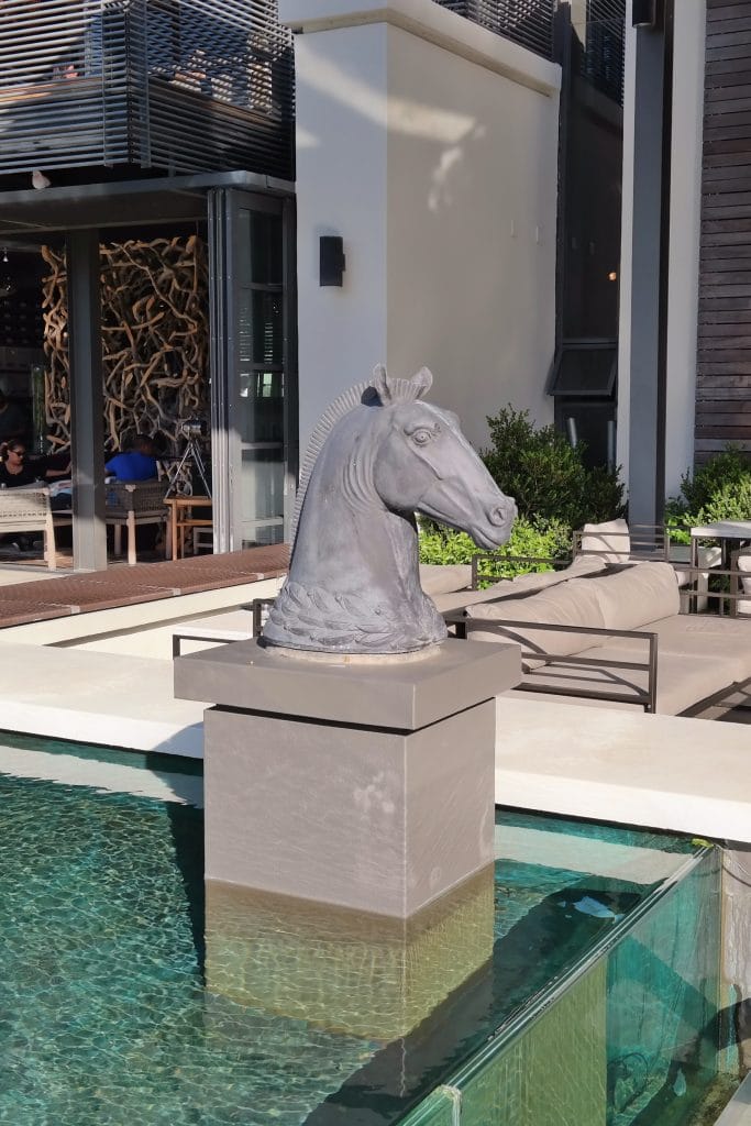 A sculpted horse head statue mounted on a pedestal, near the outdoor seating area at Steenberg.