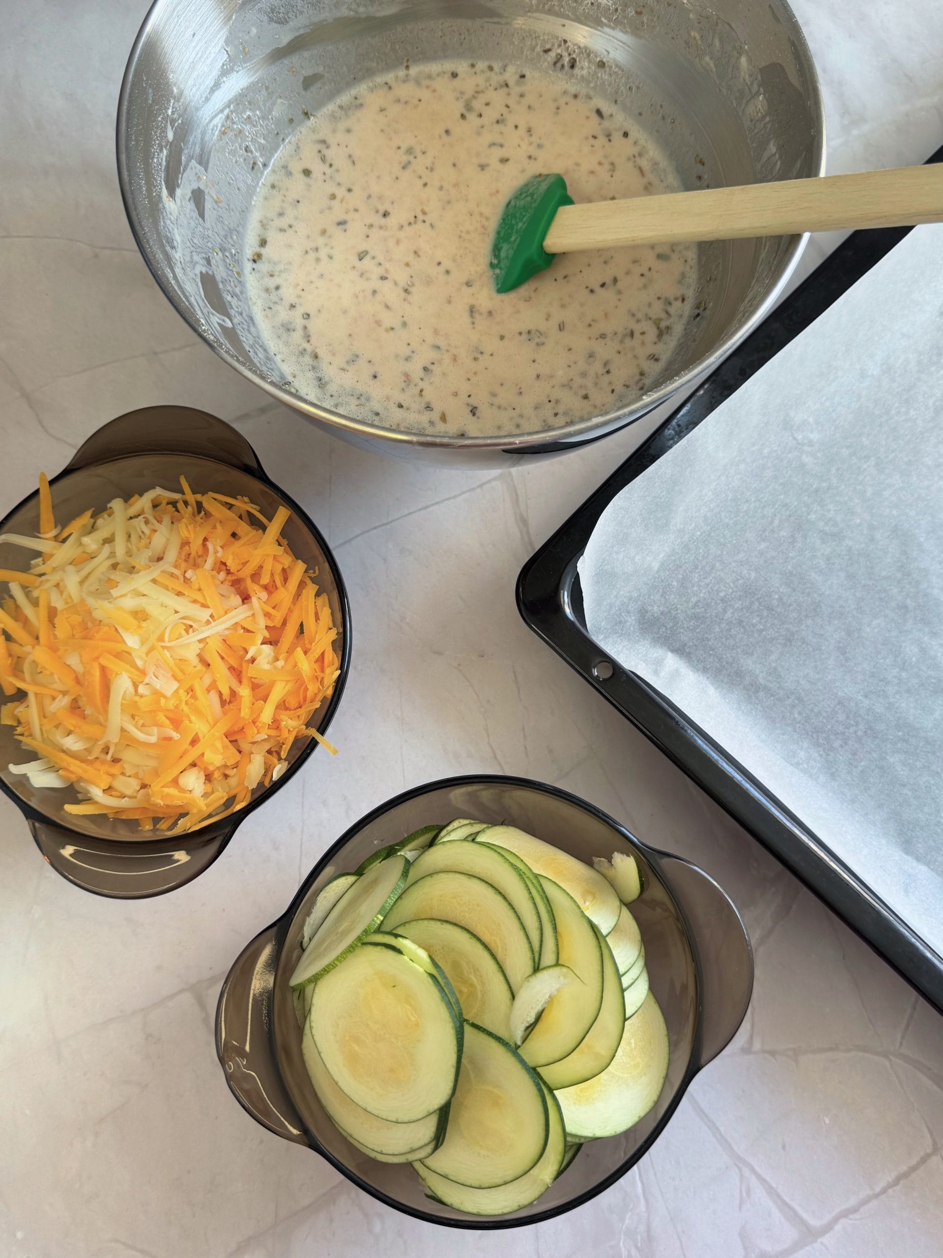 Felii de zucchini, cascaval si cheddar rase si aluatul de clatita pregatit pentru coacere