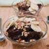 Bowls of chocolate peanut butter pudding topped with banana slices and chopped walnuts