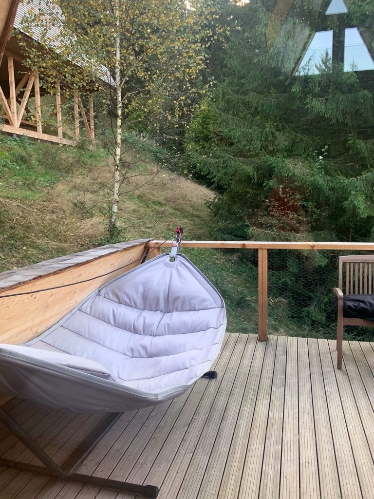 Balansoar suspendat, pe o terasă de lemn cu vedere spre deal și pădure de brazi, la Străjerii Verzi, Șirnea