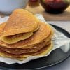 Teanc de lipii proteice rumenite pe hârtie de copt, pe o farfurie neagră, una îndoită deasupra, cu salata de pui cu morcov, chutney de mango și o salată de legume în fundal