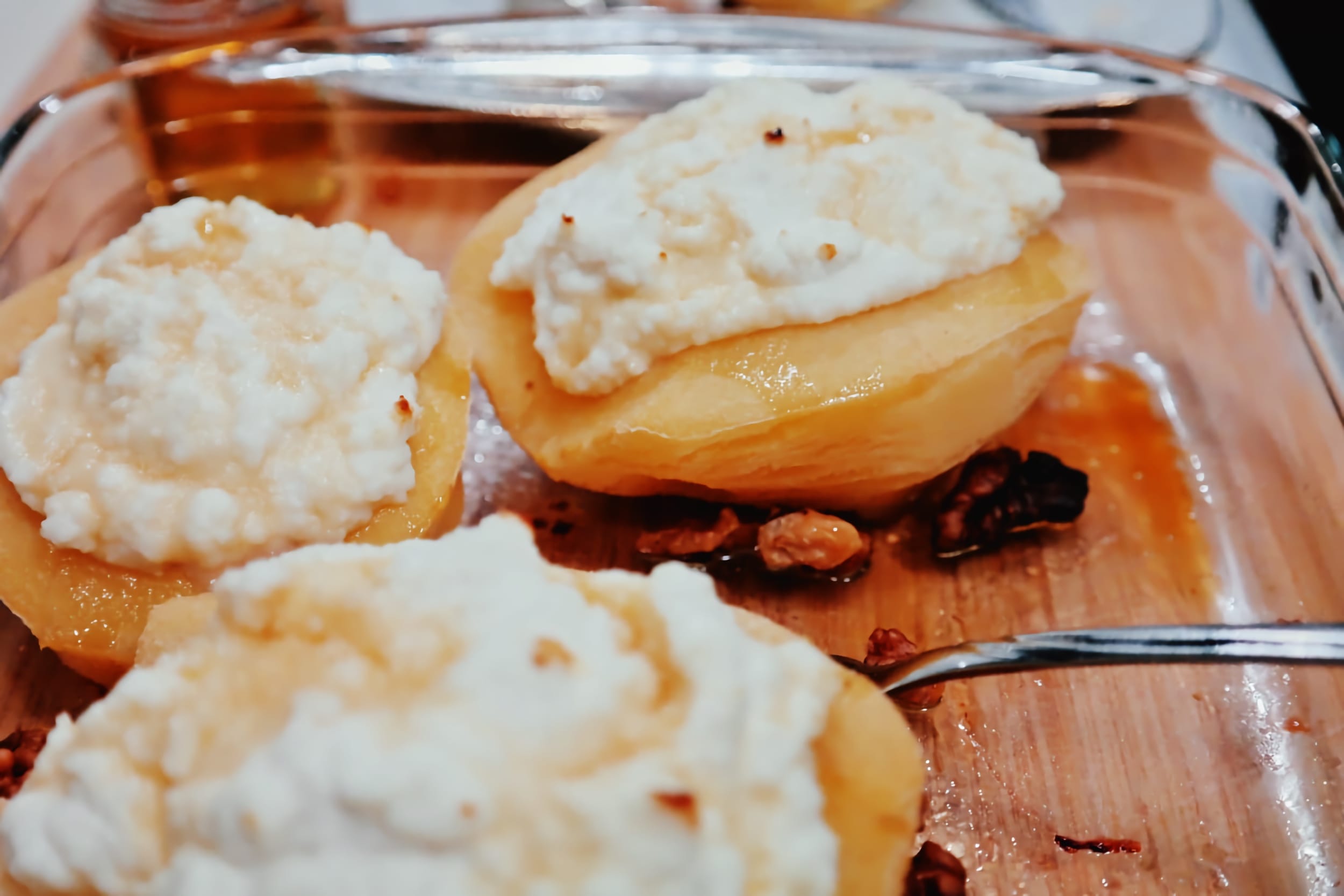 Baked quince topped with ricotta and honey in a glass baking dish
