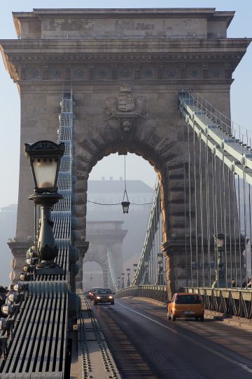 View along the Chain Bridge walkway toward its stone tower and suspension chains