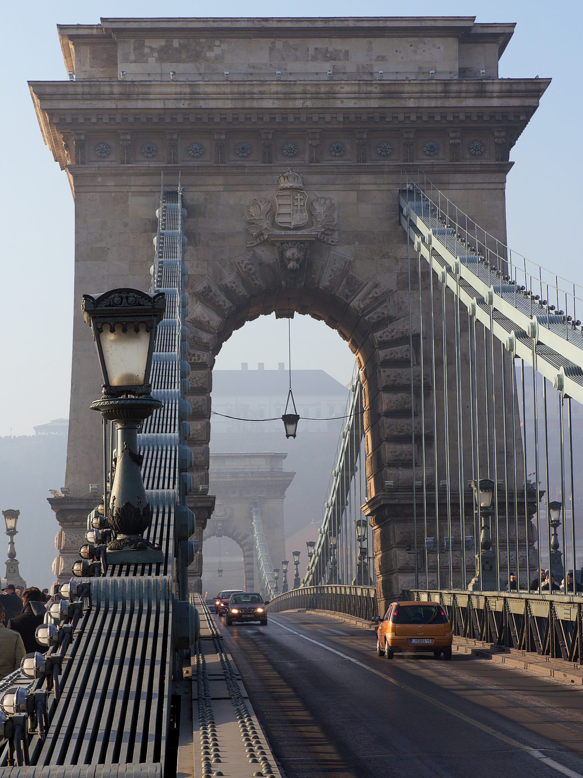 View along the Chain Bridge walkway toward its stone tower and suspension chains