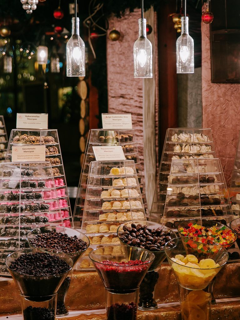 Cones of colourful sweets and clear confectionery boxes displayed at a wooden market stall