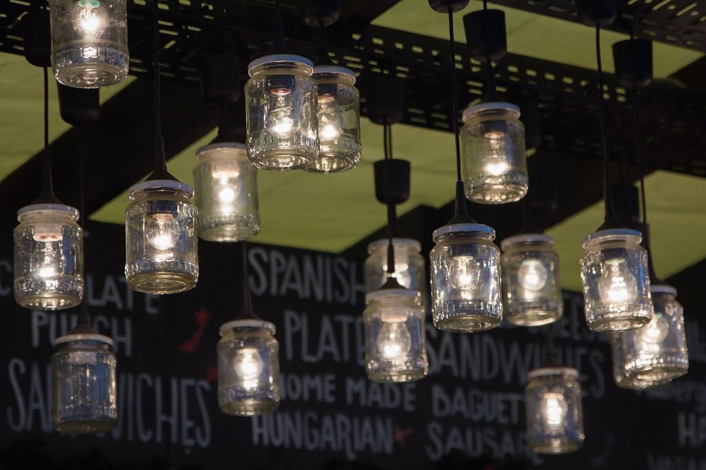 Illuminated glass jars hanging in front of a chalkboard food menu