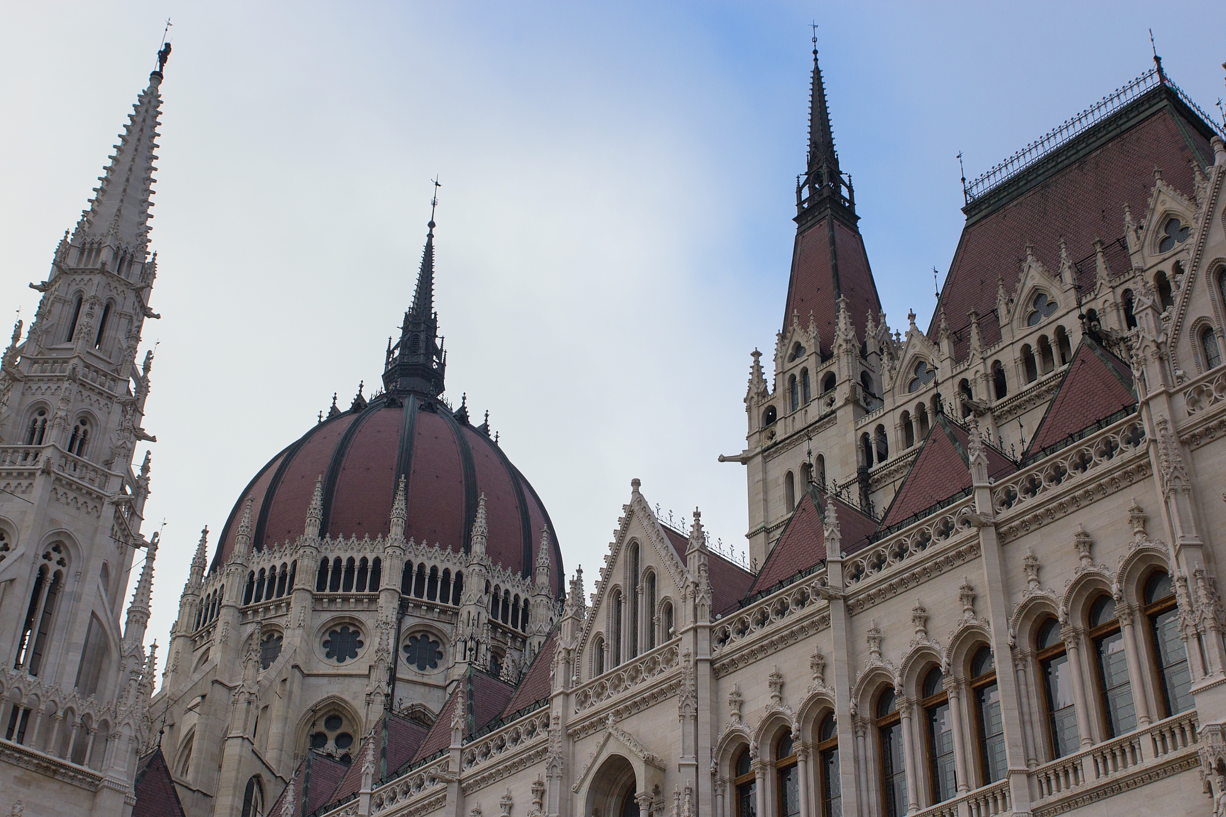 An upward view of the Hungarian Parliament’s dome and spires beneath an overcast sky