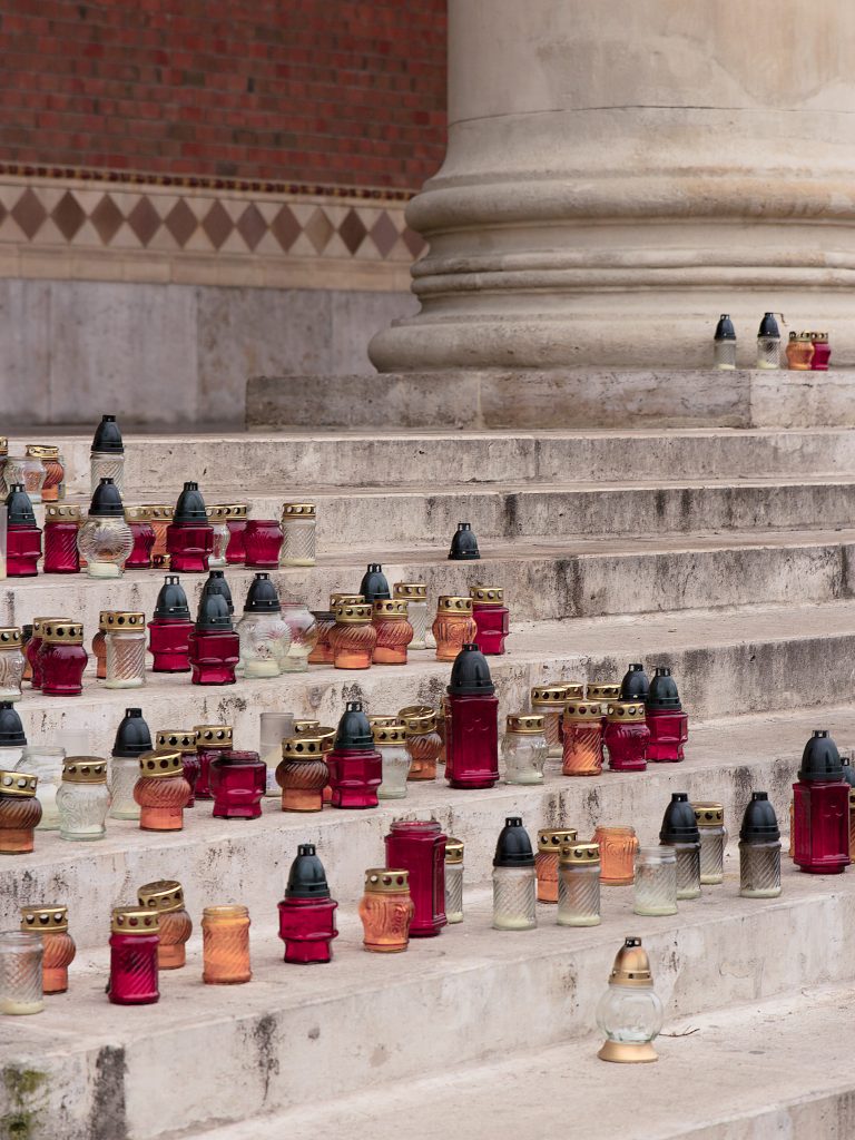 Red, yellow and clear votive candle holders arranged on stone steps beside a column