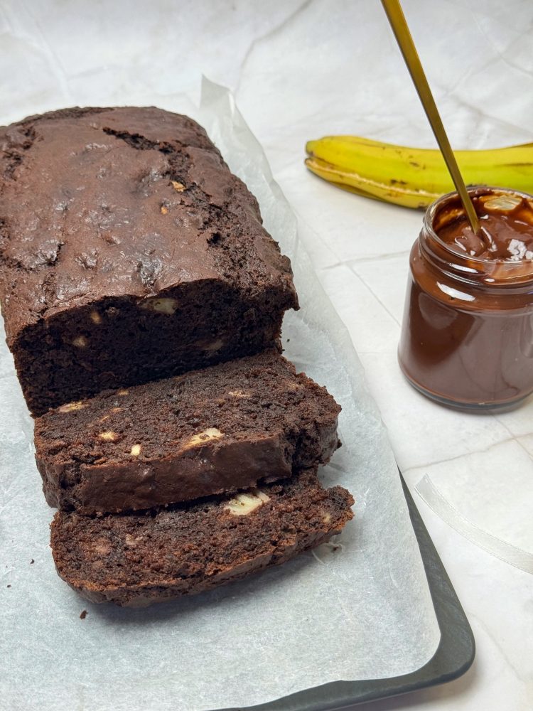 Chec cu banane și ciocolată, tăiat în felii, alături de un borcan cu ganache cremos de ciocolată și o banană