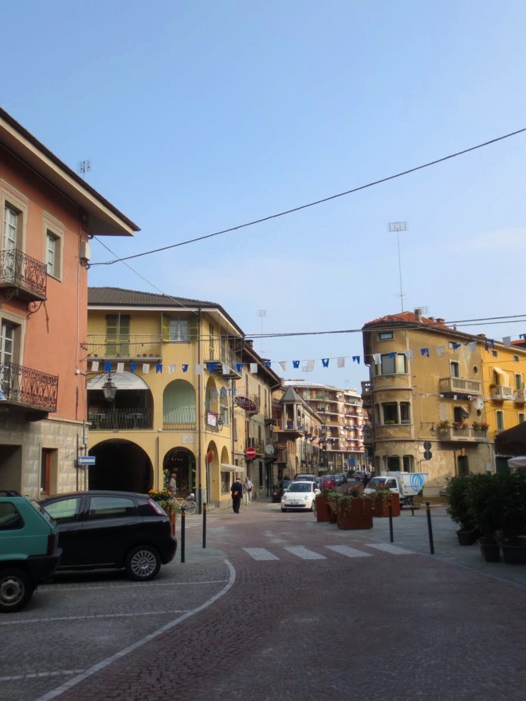 Clădiri galbene și portocalii cu balcoane și arcade, la o intersecție din Cuneo