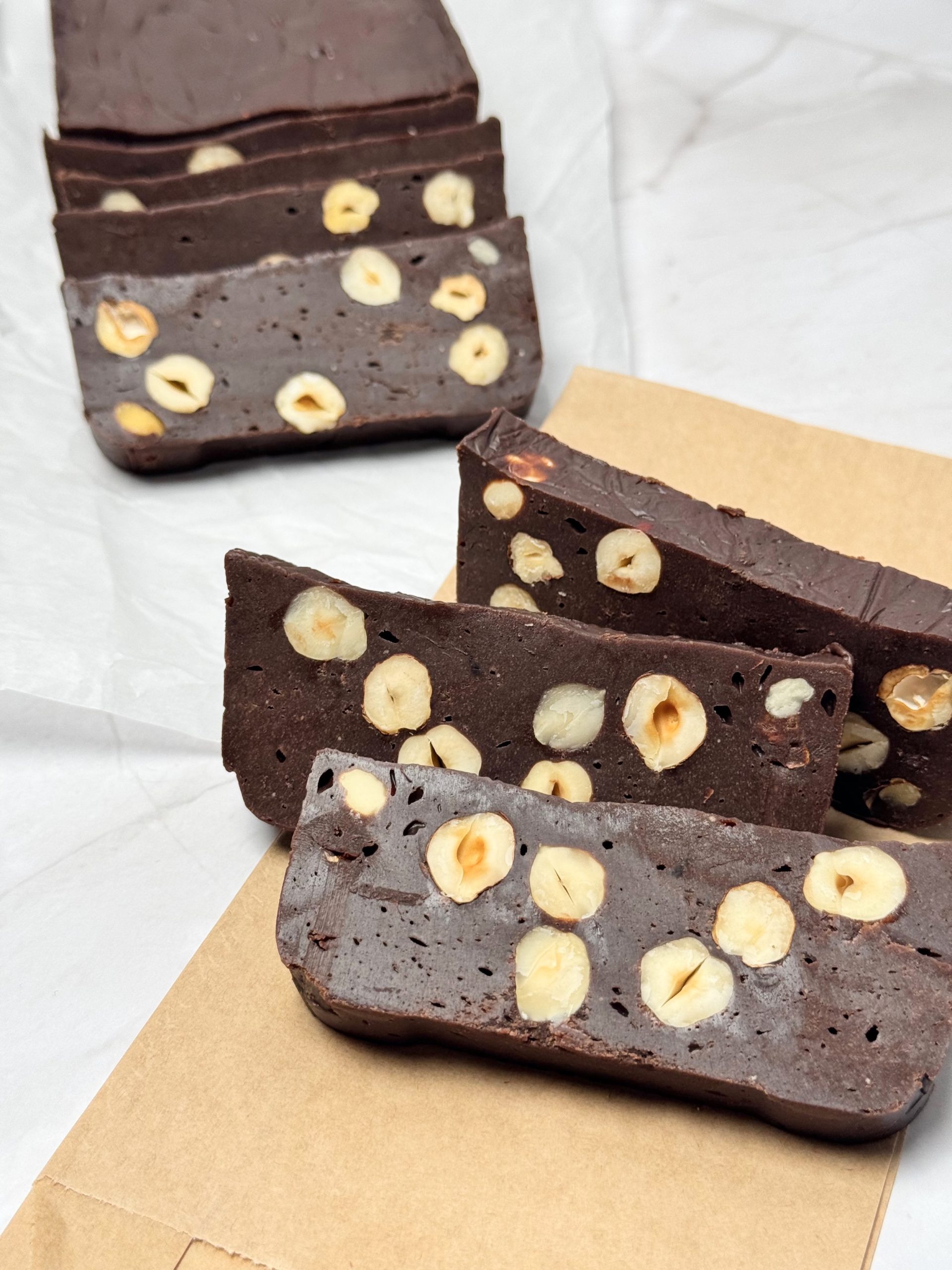 Hazelnut chocolate slices on brown paper, with the remaining chocolate loaf in the background