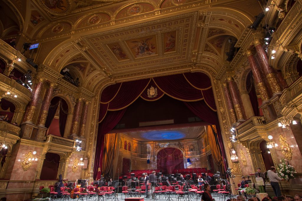 An ornate interior at the Hungarian State Opera with chairs, music stands and red drapery