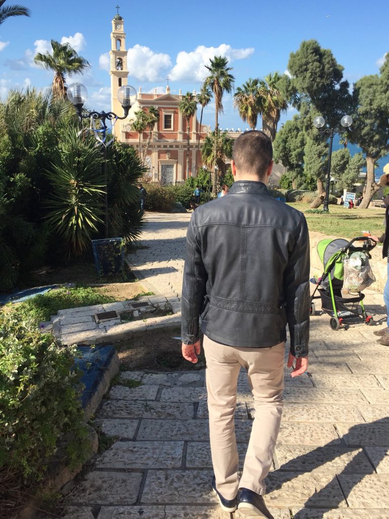 Le husband cobor&acirc;nd trepte din piatră &icirc;n Jaffa, cu palmieri și Biserica Sf&acirc;ntul Petru &icirc;n fundal