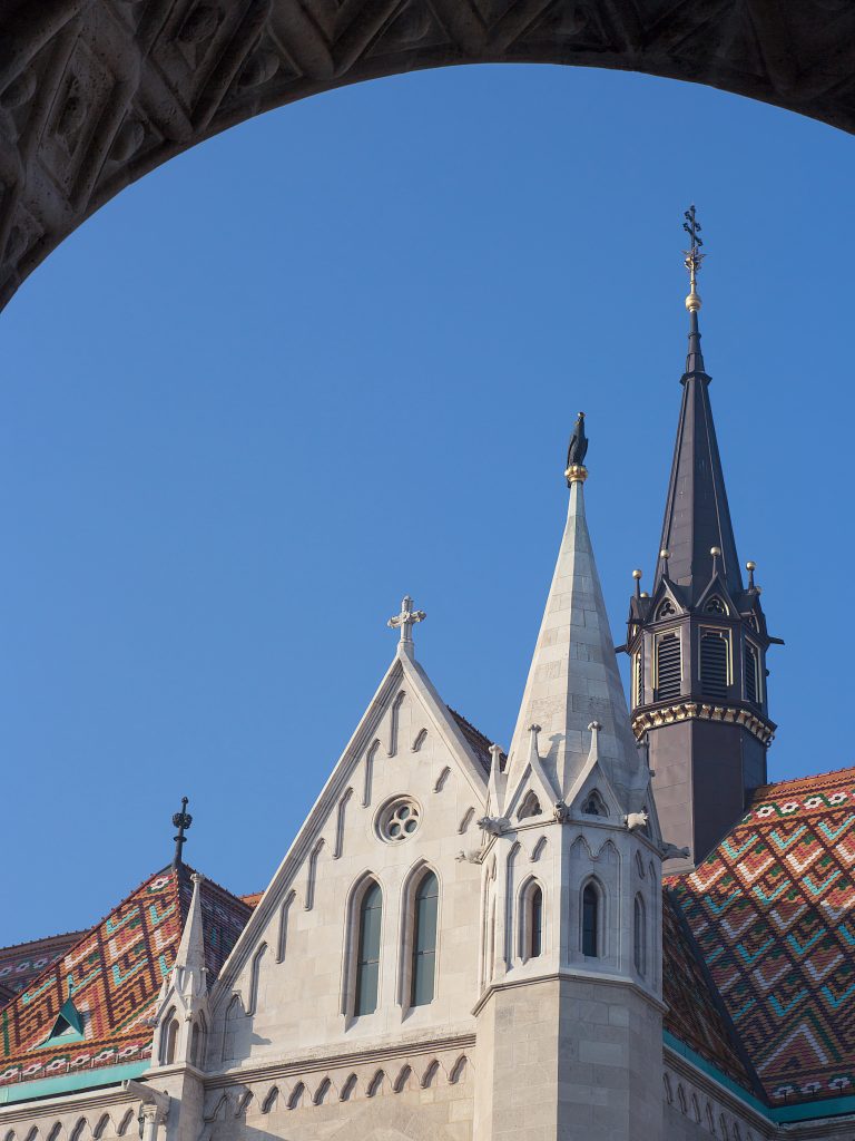 A stone arch framing Matthias Church and its colourful tiled roof