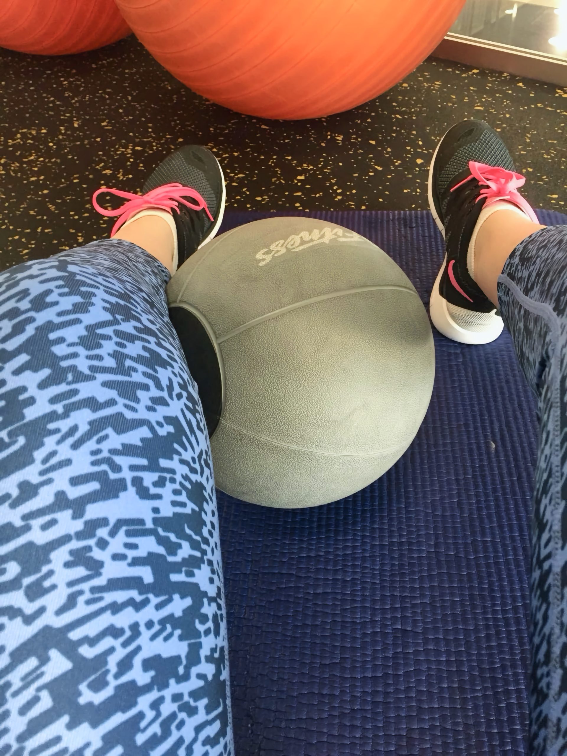 Minge medicinală pe o saltea mov, între picioare în colanți cu imprimeu și pantofi sport cu șireturi roz