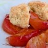 Serving of peach cobbler in a floral bowl with juicy peach slices and golden biscuit topping