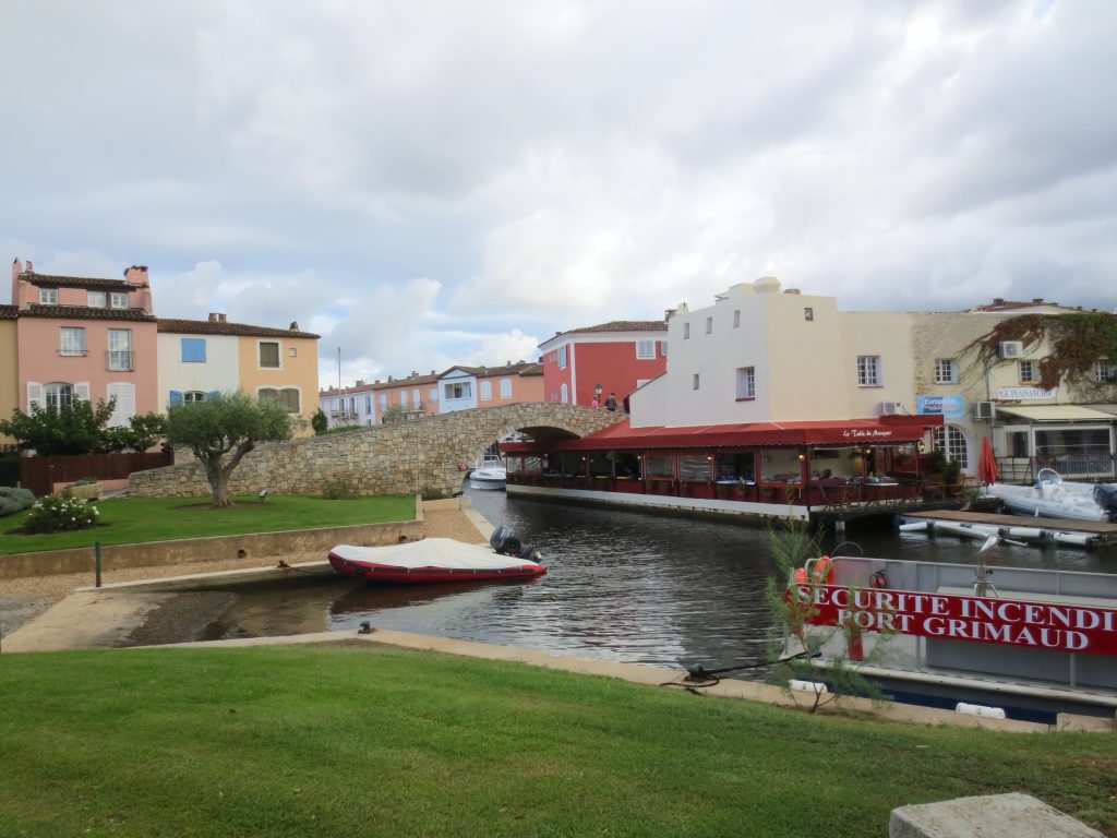 Pod peste un canal din Port Grimaud, &icirc;ntre case colorate și peluze verzi